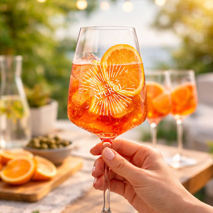 Hand hält personalisiertes Aperol Spritz Glas mit Sunburst-Gravur und Namen Nicole – sommerliche Gartenparty