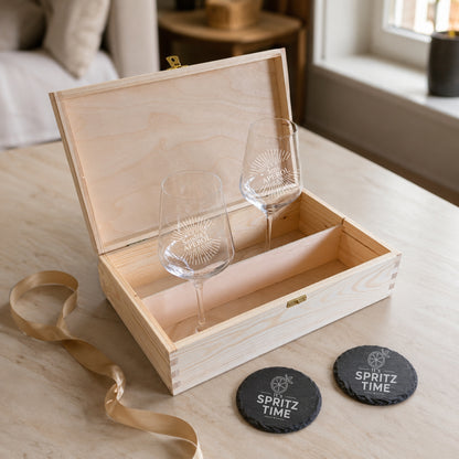 Aperol Glas personalisiert mit Namensgravur in offener Holzbox, daneben Schiefer-Untersetzer „Spritz Time