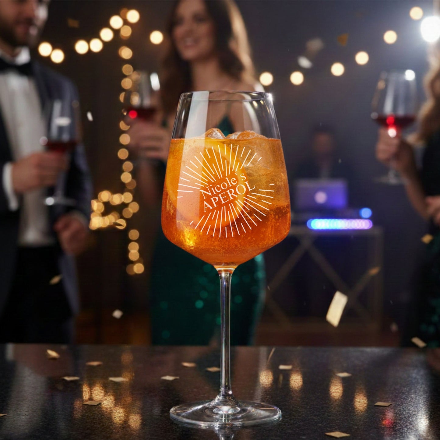 Personalisiertes Aperol Spritz Glas mit Sunburst-Gravur und Namen Nicole auf Partybar im Abendlicht