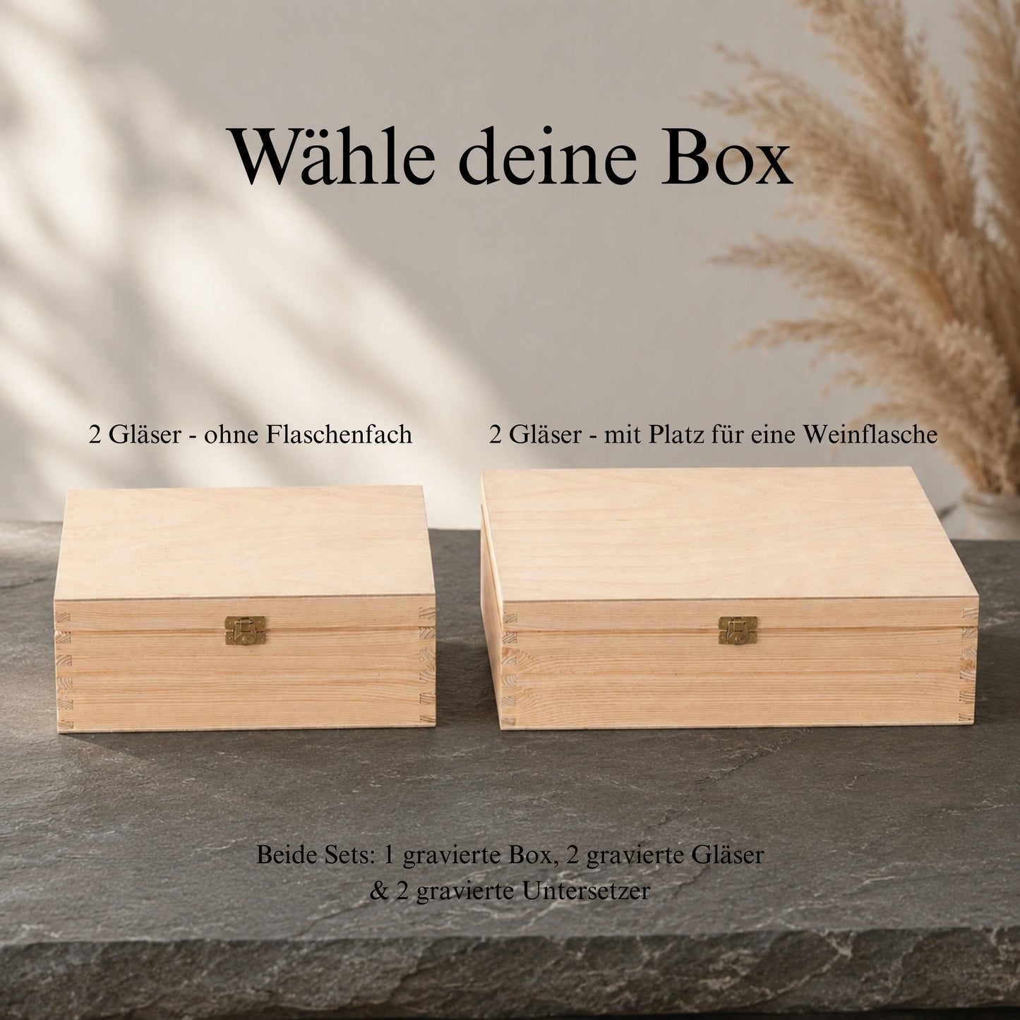 Vergleich der zwei Holzbox-Varianten für das personalisierte Weinglas-Set – links schmale Box für 2 Gläser ohne Flaschenfach, rechts breitere Box für 2 Gläser mit Platz für eine Weinflasche – beide auf Schiefer mit Pampasgras